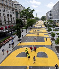 The Washington Monument and the White House are visible behind the words Black Lives Matter sign that has been painted in bright yellow letters on the 16th Street by city workers and activists, Friday, June 5, 2020, in Washington.