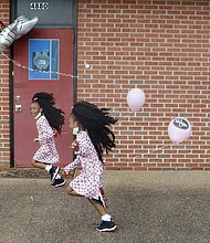 Wisdom Sadiq, 6, left, and her sister, shy Queen Sadiq, 5, have some fun following a program Aug. 8 blessing a new building now used by the H.O.P.E. Organization at 4880 Finlay St. in Henrico County. the girls, a double ball of energy, are relatives of the nonprofit’s founder, Ollie Harvey. the organization assists people with food and other needs.