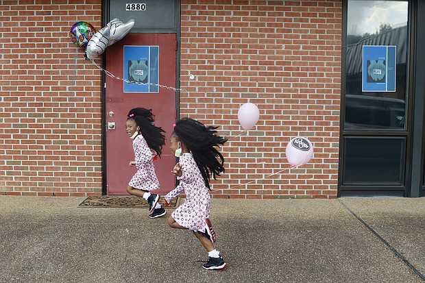 Wisdom Sadiq, 6, left, and her sister, shy Queen Sadiq, 5, have some fun following a program Aug. 8 blessing a new building now used by the H.O.P.E. Organization at 4880 Finlay St. in Henrico County. the girls, a double ball of energy, are relatives of the nonprofit’s founder, Ollie Harvey. the organization assists people with food and other needs.