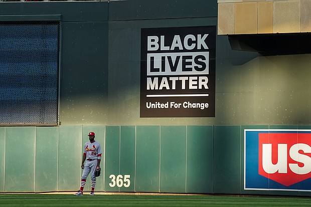 Dexter Fowler #25 of the St. Louis Cardinals looks on in front of a a wall graphic for Black Lives Matter against the Minnesota Twins on July 28, 2020 at the Target Field in Minneapolis, Minnesota. Dozens of Black baseball players will donate their salaries from Thursday and Friday to support racial justice initiatives, in honor of Jackie Robinson Day and in protest of Jacob Blake's shooting by police./Credit: Brace Hemmelgarn/Getty Images
