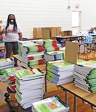 Shayla D.B. Holman, right, principal of Overby-Sheppard Elementary School in North Side, and Assistant Principal Duane Samuels survey a room packed with books and other items that parents were to pick up between 2 and 5 p.m. Thursday so students could be ready for the start of online classes Tuesday, Sept. 8.