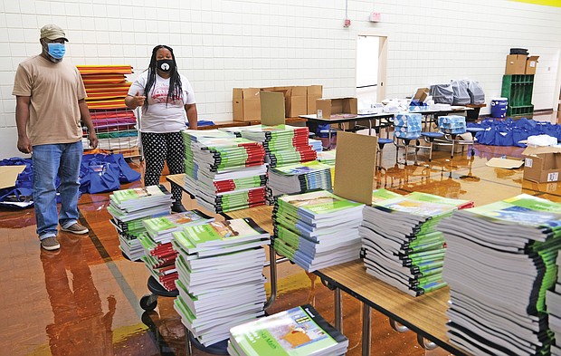 Shayla D.B. Holman, right, principal of Overby-Sheppard Elementary School in North Side, and Assistant Principal Duane Samuels survey a room packed with books and other items that parents were to pick up between 2 and 5 p.m. Thursday so students could be ready for the start of online classes Tuesday, Sept. 8.