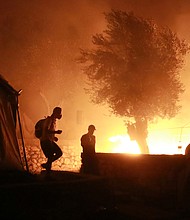 Migrants walk inside the Moria camp on the island of Lesbos during a major fire there on September 9, 2020./Credit:	Manolis Lagoutaris/AFP/Getty Images