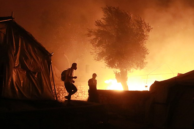 Migrants walk inside the Moria camp on the island of Lesbos during a major fire there on September 9, 2020./Credit:	Manolis Lagoutaris/AFP/Getty Images