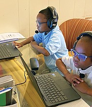 Chimborazo Elementary School students Kyle, 6, left, and Kevin Wilson, 8, connect with their teachers and classmates Tuesday, the first day of school, using Chromebooks provided by Richmond Public Schools. The kitchen table at the Wilson family’s Fulton home was turned into a virtual classroom when school began at 9:15 a.m., with mom Safiya Wilson monitoring activity.