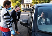 Richmond Public Schools nutritional worker Yukuri Canesius, left, and Superintendent Jason Kamras welcome Thomas Jefferson High school student Syasia Anderson and her family Tuesday morning at the meal distribution site in the parking lot of Ms. Girlee’s Kitchen in Fulton before the start of virtual classes at 9:15 a.m.