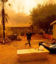 A resident runs into a home to save a dog as the Hennessey fire continues to rage near Lake Berryessa in Napa, California./Credit:	Josh Edelson/AFP via Getty Images