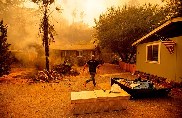 A resident runs into a home to save a dog as the Hennessey fire continues to rage near Lake Berryessa in Napa, California./Credit:	Josh Edelson/AFP via Getty Images