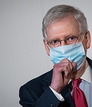 Senate Majority Leader Mitch McConnell puts on a mask after speaking to the press after a meeting with Republican Senators in the Hart Senate Office Building on Capitol Hill, May 19, 2020 in Washington, DC./Credit:	Drew Angerer/Getty Images
