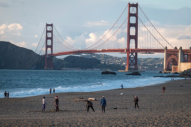 People walk at Baker Beach in March as the Golden Gate Bridge stands in the background in San Francisco./Credit:	David Paul Morris/Bloomberg/Getty Images