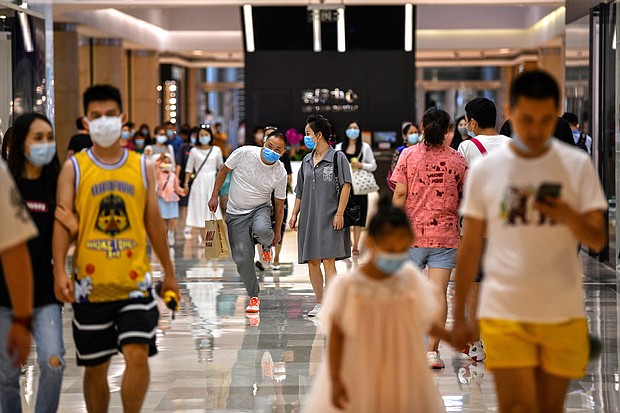 In this photo taken on September 5, 2020, people wearing face masks walk in a shopping mall in Wuhan, China's central Hubei province./Credit:	Hector Retamal/AFP/Getty Images