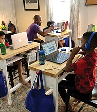 Pod leader Adam Evans works with Sebastian Wisnoski during online instruction with his Richmond Public Schools class at an education pod set up in the Evans family’s North Side home. Other youngsters in the pod are, from left, Ace Evans, Blaize Evans and Bastian Van-Zandt.