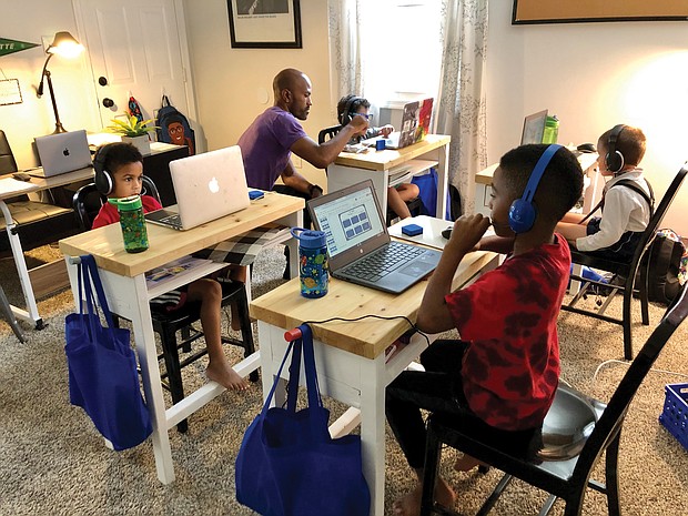 Pod leader Adam Evans works with Sebastian Wisnoski during online instruction with his Richmond Public Schools class at an education pod set up in the Evans family’s North Side home. Other youngsters in the pod are, from left, Ace Evans, Blaize Evans and Bastian Van-Zandt.