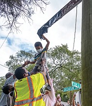 6-year-old Darren Fields, gets a lift from family and friends to unveil the street sign honoring his great-grandfather, the late Johnny R. Battle, at 32nd and Decatur streets in South Side. Mr. Battle mentored area youths and was a model neighbor.
Ms. Trammell lobbied for the sign to help ease the hurt and sense of loss for those who knew Mr. Battle, 80, who was beaten in his wheel- chair and killed during an attack in April 2018 outside his home.
