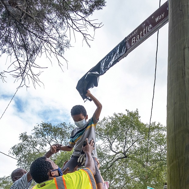 6-year-old Darren Fields, gets a lift from family and friends to unveil the street sign honoring his great-grandfather, the late Johnny R. Battle, at 32nd and Decatur streets in South Side. Mr. Battle mentored area youths and was a model neighbor.
Ms. Trammell lobbied for the sign to help ease the hurt and sense of loss for those who knew Mr. Battle, 80, who was beaten in his wheel- chair and killed during an attack in April 2018 outside his home.