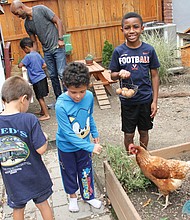 After a morning of online learning, Richmond Public Schools students in the Northside Pod Life’s elementary group use a mid-day recess to feed the chickens and gather eggs laid by hens in the backyard of pod leader Adam Evans. The youngsters are, from left, Bastian Van-Zandt (back to camera), Sebastian Wisnoski, Blaize Evans (holding egg basket) and Ace Evans with his dad and pod leader at the chicken coop.