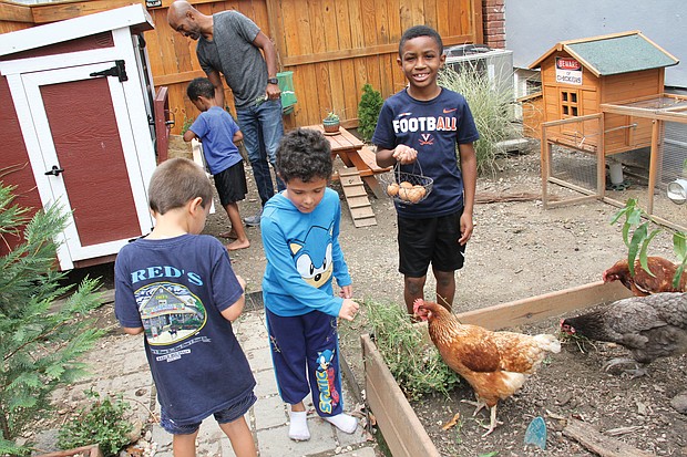 After a morning of online learning, Richmond Public Schools students in the Northside Pod Life’s elementary group use a mid-day recess to feed the chickens and gather eggs laid by hens in the backyard of pod leader Adam Evans. The youngsters are, from left, Bastian Van-Zandt (back to camera), Sebastian Wisnoski, Blaize Evans (holding egg basket) and Ace Evans with his dad and pod leader at the chicken coop.