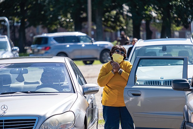 Gayle Clarke, a member of Moore Street Missionary Baptist Church, gets out of her car to listen to the sermon delivered by church pastor Dr. Alonza L. Lawrence during the church’s drive-in homecoming service last Sunday in the parking lot of Hovey Field at Virginia Union University.