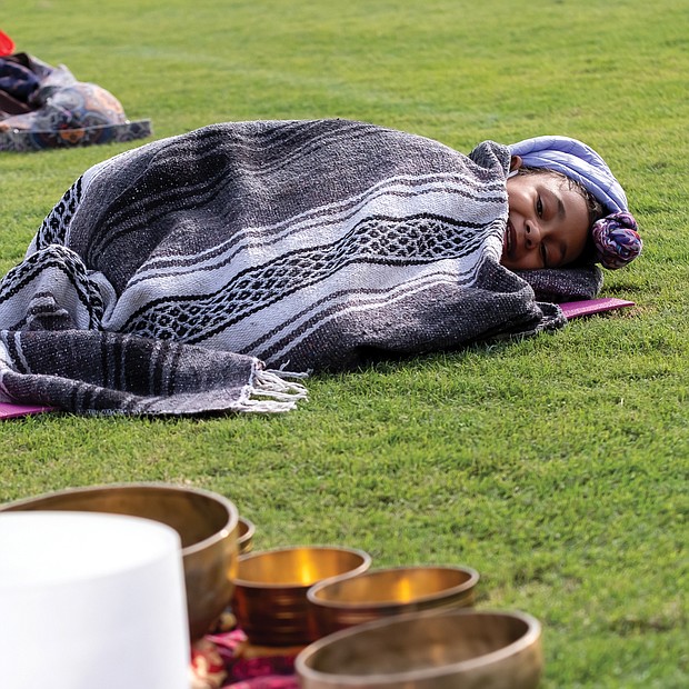 Treasure Daily, 10, bundles up in the chilly outfield of The Diamond last Saturday and listens as her mother, Shanna Latia, conducts a sound therapy session during Project Yoga Richmond’s Saturday Salutations. The nonprofit sponsoring organization is dedicated to making yoga accessible and affordable to Richmonders. The next Saturday Salutations session is scheduled for 9 to 10 a.m. Saturday, Oct. 17, at The Diamond on Arthur Ashe Boulevard.