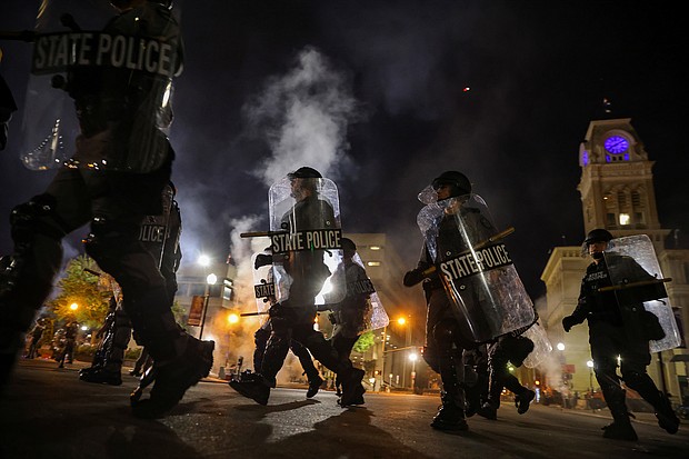 Police officers move past Louisville City Hall on Sept. 23 as a curfew is implemented at 9pm to disperse protesters after a grand jury voted to indict one of three white police officers for wanton endangerment in the death of Breonna Taylor, who was shot dead by police in her apartment, in Louisville, Kentucky./Credit: Carlos Barria/Reuters