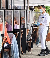 A waiter wears a face mask and rubber gloves outside Peter Luger Steakhouse in Williamsburg as the city continues Phase 4 of re-opening following restrictions imposed to slow the spread of coronavirus on September 10, 2020 in New York City./Credit:	Noam Galai/Getty Images