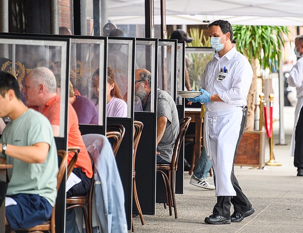 A waiter wears a face mask and rubber gloves outside Peter Luger Steakhouse in Williamsburg as the city continues Phase 4 of re-opening following restrictions imposed to slow the spread of coronavirus on September 10, 2020 in New York City./Credit:	Noam Galai/Getty Images