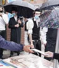 Brooklyn Borough President Eric Adams hands out a mask Tuesday./Credit:	Carlo Allegri/Reuters
