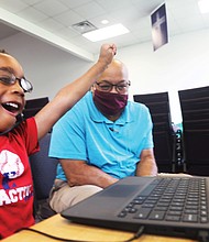 Kayden Bass, 6, a first-grader at Fairfield Court Elementary School, cheers himself on for the answer he gave during his virtual class Tuesday. He is part of the Project Stay Connected/Stay on Point learning pod, where volunteer Arthur Gregory, a retired DuPont employee, works with students.