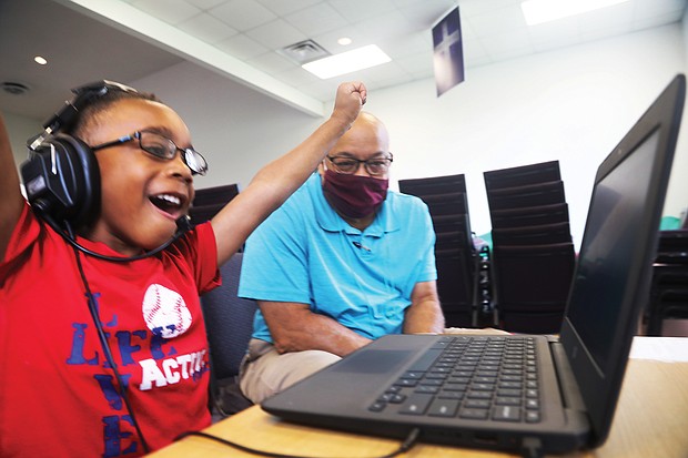 Kayden Bass, 6, a first-grader at Fairfield Court Elementary School, cheers himself on for the answer he gave during his virtual class Tuesday. He is part of the Project Stay Connected/Stay on Point learning pod, where volunteer Arthur Gregory, a retired DuPont employee, works with students.