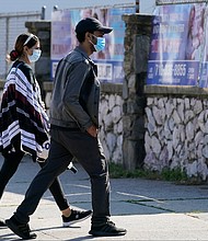 Two people wear protective face masks as they walk along a commercial street in the Gravesend section of the Brooklyn borough of New York on September 28, 2020.
Credit:	Kathy Willens/AP