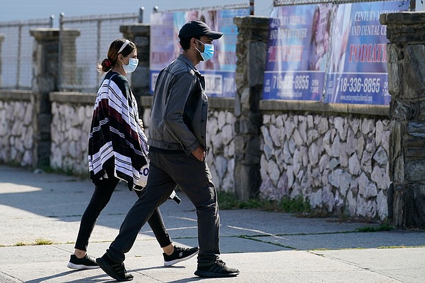 Two people wear protective face masks as they walk along a commercial street in the Gravesend section of the Brooklyn borough of New York on September 28, 2020.
Credit:	Kathy Willens/AP