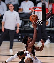 The Miami Heat’s Jimmy Butler (22) goes for a layup against the Los Angeles Lakers’ LeBron James (23) during the second half in Game 3 on Sunday of basketball’s NBA Finals in Lake Buena Vista, Fla.