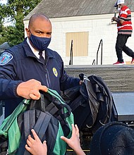 Chief Smith hands out backpacks to youngsters at National Night Out.