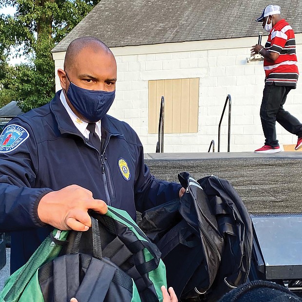 Chief Smith hands out backpacks to youngsters at National Night Out.