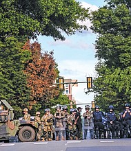 Richmond Police officers stand with National Guard members and Virginia State Police troopers at Madison and Grace near Police Headquarters in June in Downtown Richmond.