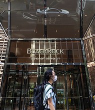 A pedestrian wearing a protective mask walks past BlackRock Inc. headquarters in New York on July 9, 2020./Credit:	Jeenah Moon/Bloomberg/Getty Images