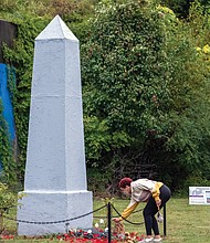 Taylor Maloney lays a white rose at the base of the obelisk honoring Richmond’s enslaved population during last Saturday’s 18th Annual Gabriel Gathering held at the burial ground for enslaved Africans in Shockoe Bottom.