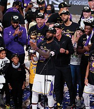 Los Angeles Lakers LeBron James holds his fourth Finals MVP award as he celebrates the Lakers’ win Sunday over the Miami Heat with his teammates in Lake Buena Vista, Fla.