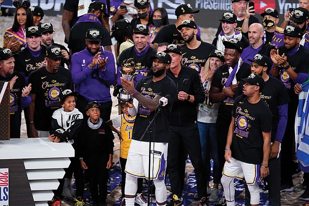 Los Angeles Lakers LeBron James holds his fourth Finals MVP award as he celebrates the Lakers’ win Sunday over the Miami Heat with his teammates in Lake Buena Vista, Fla.