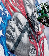 Celebrated Richmond muralist Hamilton Glass completes his latest addition to the city’s streetscape — a dramatic work that features black faces infused into the traditional red, white and blue and stars of the American flag. A clear artistic statement of the message that Black Lives Matter, the mural faces the Brookland Park Boulevard side of the Richmond Urban Ministry Institute at the intersection of Chamberlayne Avenue and Brookland Park Boulevard in North Side. New murals continue to be added. On Wednesday, the city unveiled Josh Zarambo’s mural tribute to the late Congressman John Lewis of Georgia at the Powhatan Community Center on Fulton Hill. And recently, another well-known muralist, Sir James Thornhill, completed a new mural with student help in the 800 block of Oliver Hill Way in Shockoe Bottom.