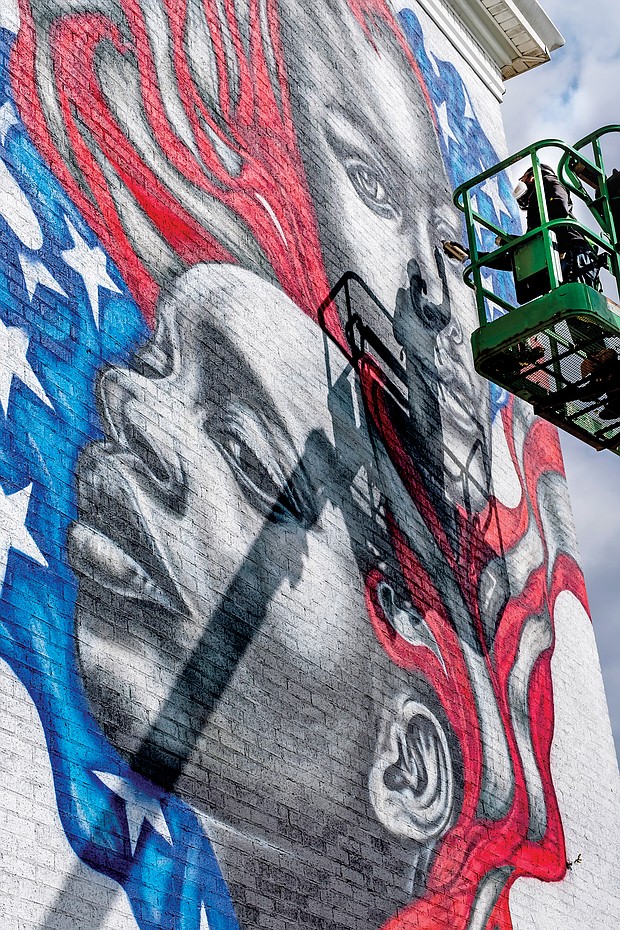 Celebrated Richmond muralist Hamilton Glass completes his latest addition to the city’s streetscape — a dramatic work that features black faces infused into the traditional red, white and blue and stars of the American flag. A clear artistic statement of the message that Black Lives Matter, the mural faces the Brookland Park Boulevard side of the Richmond Urban Ministry Institute at the intersection of Chamberlayne Avenue and Brookland Park Boulevard in North Side. New murals continue to be added. On Wednesday, the city unveiled Josh Zarambo’s mural tribute to the late Congressman John Lewis of Georgia at the Powhatan Community Center on Fulton Hill. And recently, another well-known muralist, Sir James Thornhill, completed a new mural with student help in the 800 block of Oliver Hill Way in Shockoe Bottom.