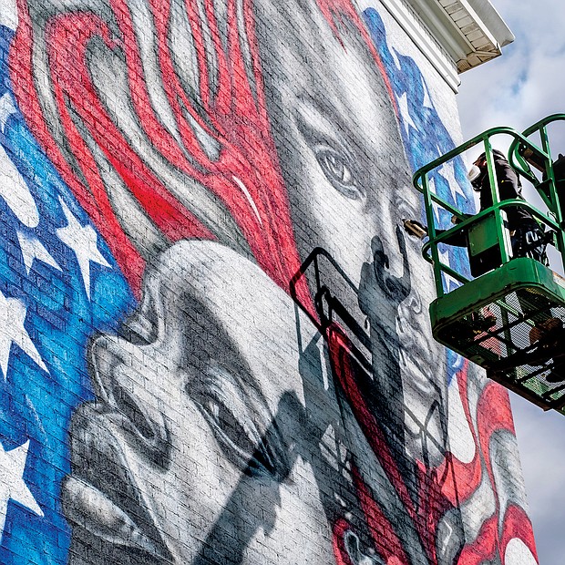 Celebrated Richmond muralist Hamilton Glass completes his latest addition to the city’s streetscape — a dramatic work that features black faces infused into the traditional red, white and blue and stars of the American flag. A clear artistic statement of the message that Black Lives Matter, the mural faces the Brookland Park Boulevard side of the Richmond Urban Ministry Institute at the intersection of Chamberlayne Avenue and Brookland Park Boulevard in North Side. New murals continue to be added. On Wednesday, the city unveiled Josh Zarambo’s mural tribute to the late Congressman John Lewis of Georgia at the Powhatan Community Center on Fulton Hill. And recently, another well-known muralist, Sir James Thornhill, completed a new mural with student help in the 800 block of Oliver Hill Way in Shockoe Bottom.