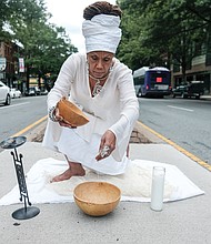 Janine Bell, president and artistic director of the Elegba Folklore Society, pours a libation honoring the ancestors at 1st and Broad streets in Downtown. The libation was part of the society’s “Juneteenth 2020: A Freedom Celebration” that was shown virtually on June 20. The crossroad was chosen to symbolize the point at which a crucial decision must be made that will have far-reaching consequences culturally, locally, regionally and nationally.