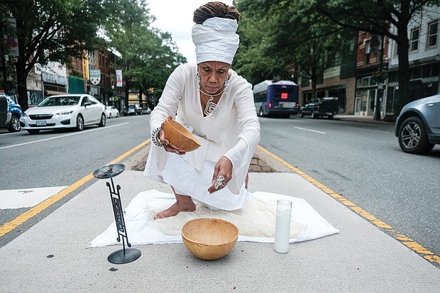 Janine Bell, president and artistic director of the Elegba Folklore Society, pours a libation honoring the ancestors at 1st and Broad streets in Downtown. The libation was part of the society’s “Juneteenth 2020: A Freedom Celebration” that was shown virtually on June 20. The crossroad was chosen to symbolize the point at which a crucial decision must be made that will have far-reaching consequences culturally, locally, regionally and nationally.