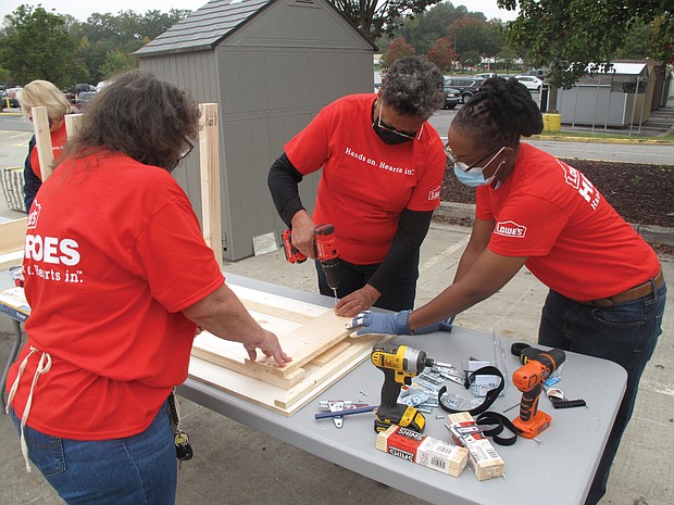 Richmond City Councilwoman Ellen F. Robertson, center, assembles a desk with the help of Anita Sawyer, left, and Fatemia Gunter, two employees of Lowe’s home improvement store. Employees at the Sheila Lane store in South Side volunteered to put together 500 fold-up desks for Richmond Public Schools students who are learning at home during the pandemic. About 25 Lowe’s employees started the project last week, with 100 desks being produced each Tuesday. The desks will be given to students free of charge.
