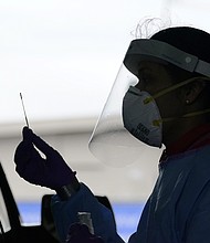 University of Washington research coordinator Rhoshni Prabhu holds up a swab after testing a passenger at a free COVID testing site in Seattle.
Credit:	Elaine Thompson/AP