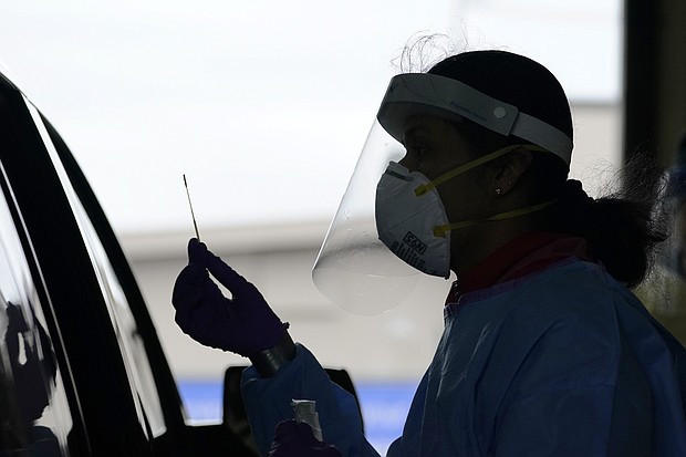 University of Washington research coordinator Rhoshni Prabhu holds up a swab after testing a passenger at a free COVID testing site in Seattle.
Credit:	Elaine Thompson/AP