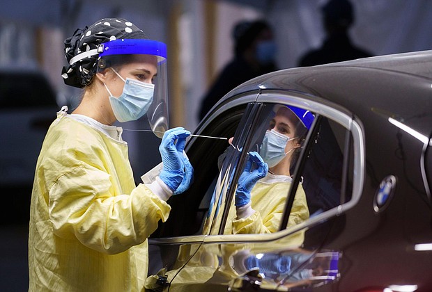 A nurse collects a sample on a patient at a drive-thru Covid-19 clinic in Montreal on October 21, 2020.
Credit:	Paul Chiasson/The Canadian Press/AP