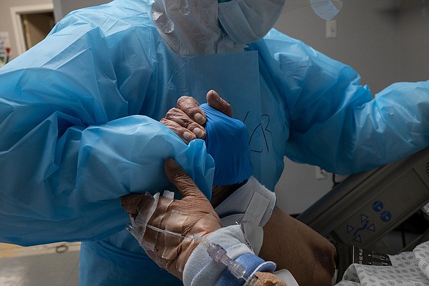 A medical staff member grabs a hand of a patient to reposition the bed in the COVID-19 intensive care unit at the United Memorial Medical Center on October 31, 2020 in Houston, Texas./Credit:	Go Nakamura/Getty Images