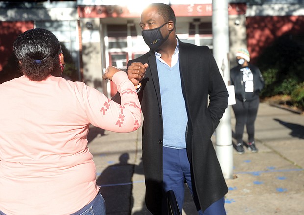 Mayor Levar M. Stoney greets a voter Tuesday as she heads to cast her ballot at Precinct 701 inside Woodville Elementary School in the East End. The mayor’s re-election campaign paid off with victory in six of the city’s nine districts, including the 7th District, where the school is located.